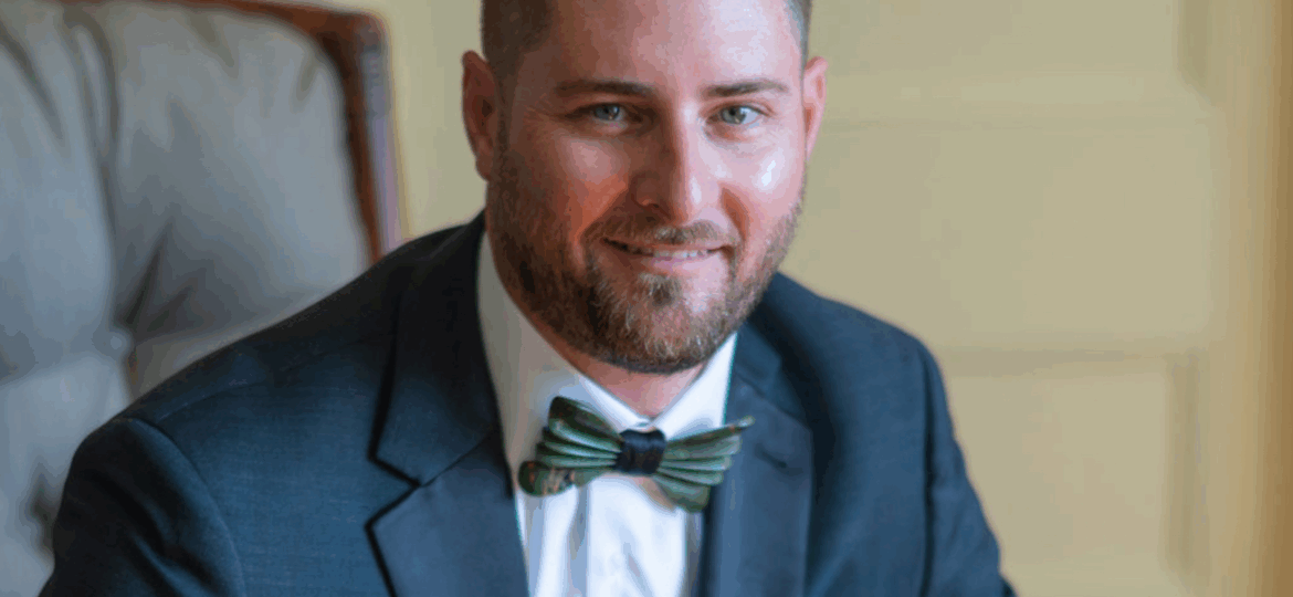 Jamie Nall sitting in a suit and bowtie